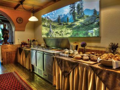 Gemütlicher Frühstücksraum mit vielfältigem Brot- und Brötchenbuffet an langer Theke.