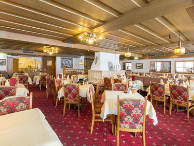 Amplio comedor con alfombras rojas, manteles blancos y sillas tapizadas con flores.