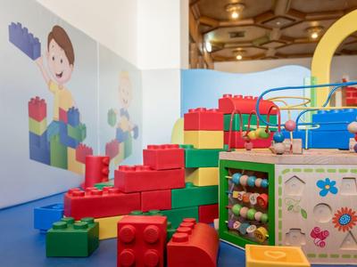 Buntes Indoor-Spielzimmer mit großen Bausteinen, Motorikschleife und Wandillustrationen.