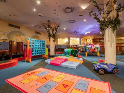 Bunter Indoor-Spielbereich mit Klettergerüsten, Hüpfcups und Spielzeugautos auf Teppichboden.