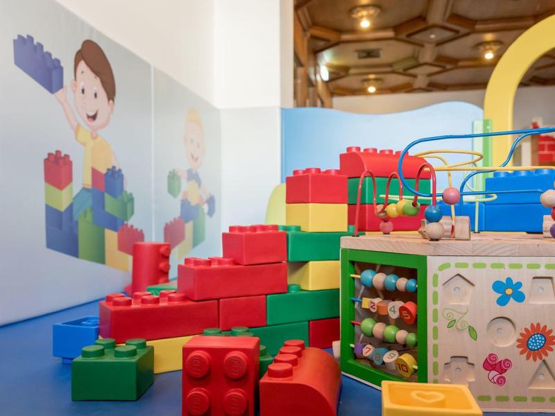 Buntes Indoor-Spielzimmer mit großen Bausteinen, Motorikschleife und Wandillustrationen.