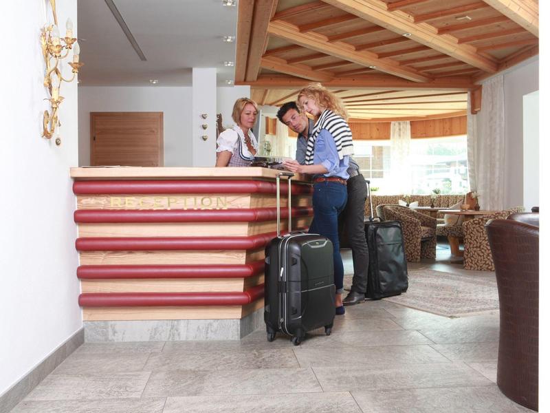 Zwei Personen mit Koffern checken an einer Hotelrezeption ein.