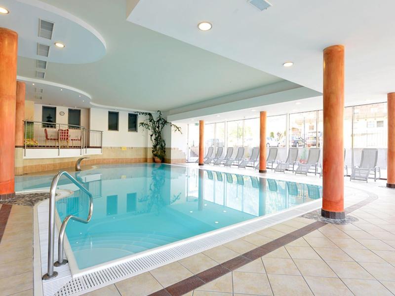 Helles Hallenbad mit orangenen Säulen und großen Fenstern