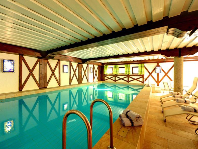 Heller Innenpool mit Holzträgern, liegenden Stühlen und weißen Handtüchern am Beckenrand.