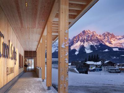 Hotel entrance area with a view of snowy mountains at sunset.