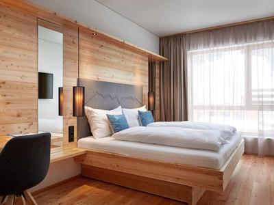 Modern hotel room with wooden accents, large bed, and plenty of natural light.
