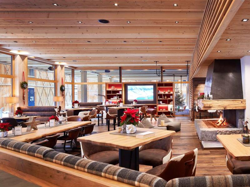 Gemütliches Restaurant mit Holztischen, gepolsterten Bänken und warmem Kaminfeuer.