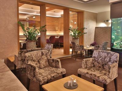 Gemütlicher Aufenthaltsraum mit braunen Sesseln, Holztischen und großem Aquarium.