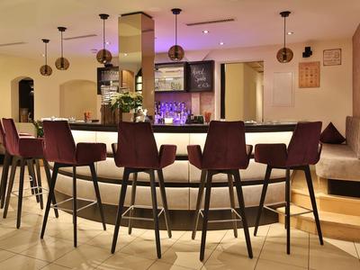 Moderner Bartresen mit hohen Stühlen, Pendelleuchten und gemütlicher Atmosphäre in warmen Farben.