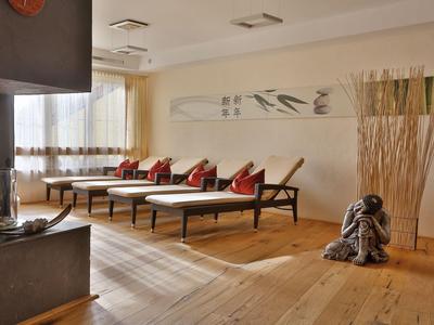 Moderní odpočinková místnost s lehátky, červeno-bílými polštáři a dřevěnou podlahou v hotelu.