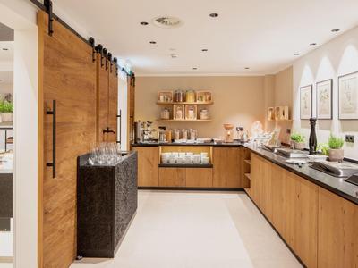 Moderne Küche mit Holzschränken, schwarzen Arbeitsplatten und hellen Wänden, hell beleuchtet.