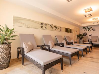 Gemütlicher Ruhebereich mit Liegestühlen, Pflanzen und sanfter Beleuchtung in hellem Raum.