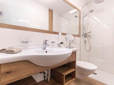 Modernes Badezimmer mit weißer Keramik, Holzmöbeln und großer Spiegelwand.