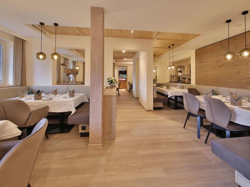 Gemütlicher Restaurantraum mit hellen Holzmöbeln, bequemen Stühlen und warmem Licht.