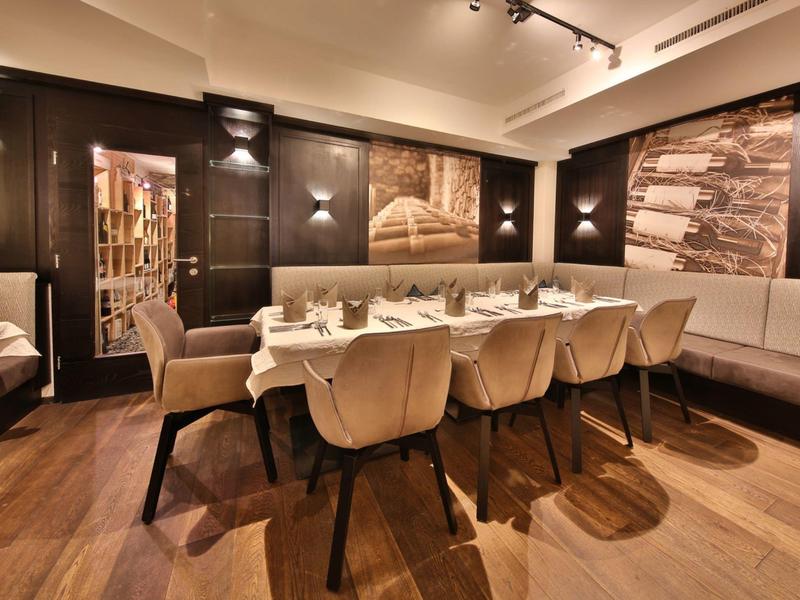 Moderner Essbereich mit langen weißen Tischen, bequemen Stühlen und warmem Holzboden.