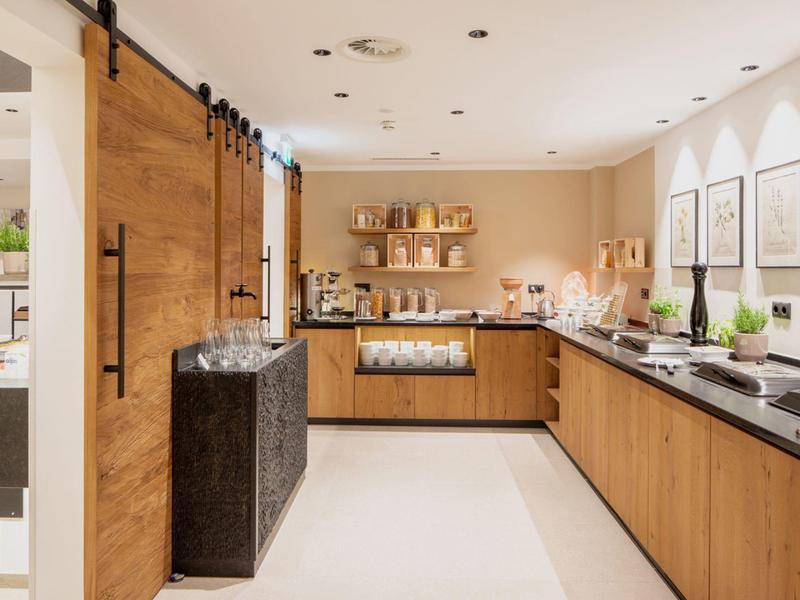 Moderne Küche mit Holzschränken, schwarzen Arbeitsplatten und hellen Wänden, hell beleuchtet.