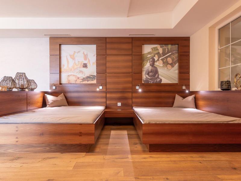 Symmetrisches Schlafzimmer mit zwei Holzbettgestellen, beigen Matratzen und dunklen Kissen.