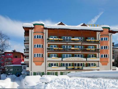 Mehrstöckiges Hotel mit Balkonen und Schnee im Vordergrund an einem klaren Wintertag