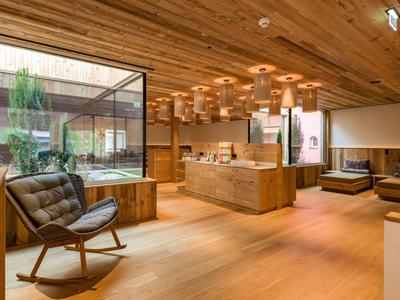 Modern lounge area with wooden furniture, leather chair, and view of a courtyard with plants.