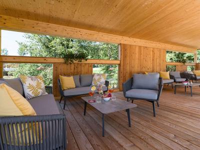 Überdachte Terrasse mit Holzverkleidung und moderner Sitzgruppe mit Sofas und einem Tisch.