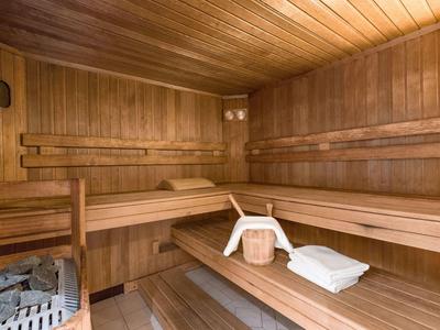 Sauna mit Holzwänden, Holzbänken, Eimer, Kelle und weißen Handtüchern.