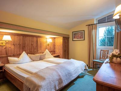 Cozy hotel room with double bed, wooden furniture, and balcony access with a view.
