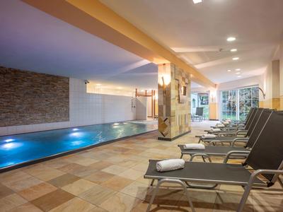 Beheiztes Hallenbad mit Liegestühlen und Handtüchern in stilvollem Spa-Bereich.