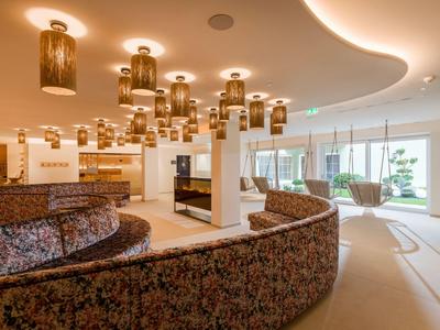 Bright modern hotel lobby with curved seating and numerous ceiling lights.