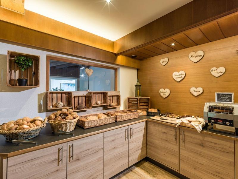 Gemütliche Frühstücksecke mit Brotkörben und Kaffeemaschine in warm beleuchtetem Hotelbereich.