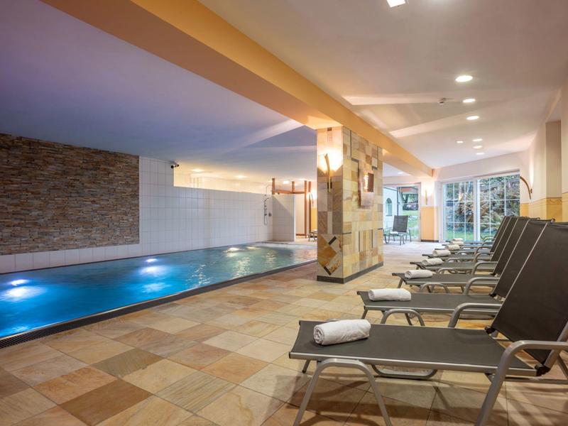 Beheiztes Hallenbad mit Liegestühlen und Handtüchern in stilvollem Spa-Bereich.