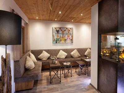 Gemütliche Sitzecke mit Polstersofas, Kissen, Kamin und warmer Beleuchtung in einem Hotel.