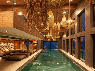 Moderner Innenpool mit hölzernen Deckendetails, großen Fenstern und bequemen Sitzbereichen.