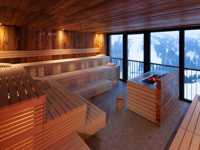Angenehm beleuchtete Holzsauna mit großen Fenstern und Bergblick.