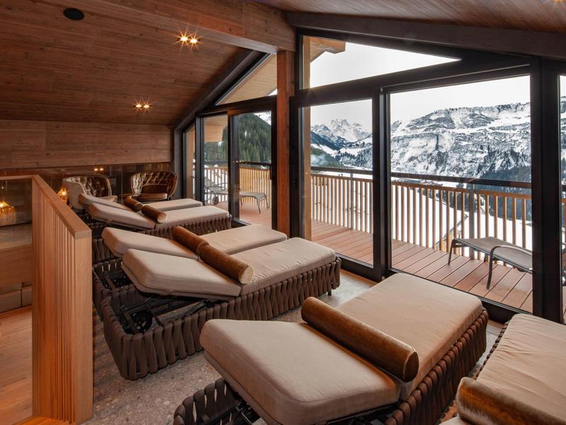 Gemütlicher Ruheraum mit gepolsterten Liegen und Panoramafenstern mit Blick auf verschneite Berge.