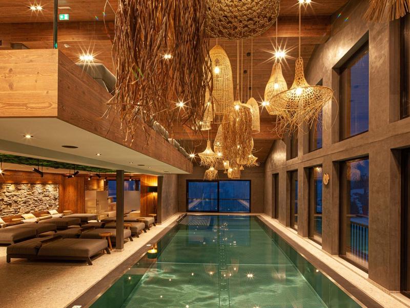 Moderner Innenpool mit hölzernen Deckendetails, großen Fenstern und bequemen Sitzbereichen.