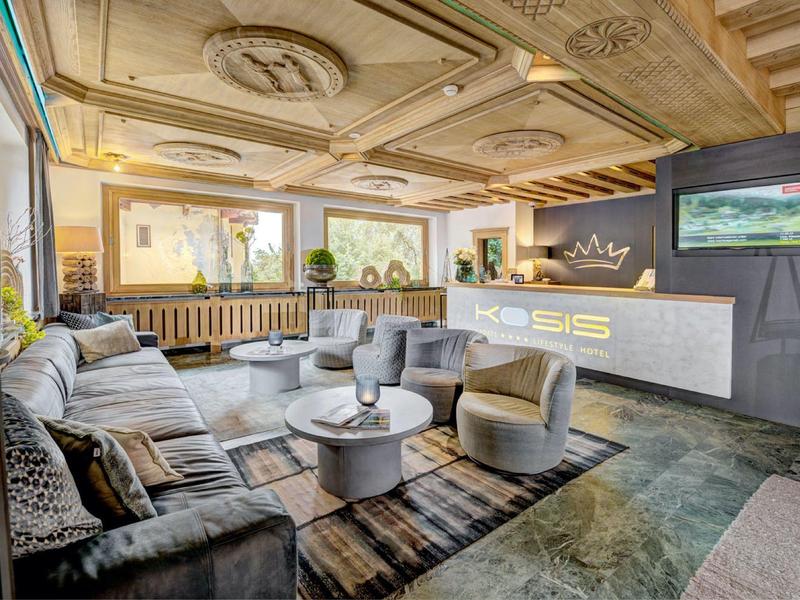 Moderne Lobby mit grauem Sofa, weißen Sesseln, rundem Tisch und hellen Holzelementen.