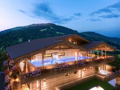 Gemütliche Berghütte mit beleuchtetem Außenpool und Panorama im Abendlicht.
