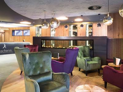 Moderne hotelhal met kleurrijke stoelen en receptiebalie op de achtergrond.