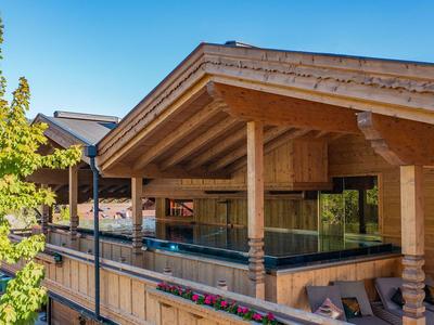 Modern houten hotelcomplex met glazen balkons en uitzicht op de bergen bij heldere lucht.