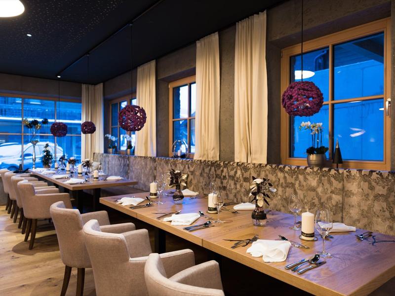 Eleganter Hotelrestaurantbereich mit dunkler Decke und modernen Holztischen bei Abenddämmerung.