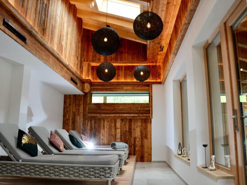 Moderner Hotel-Indoor-Ruheraum mit Liegen, Holzwänden und großen schwarzen Hängeleuchten