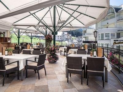Overdekt buitenterras met tafels en stoelen in een moderne hotelsfeer.