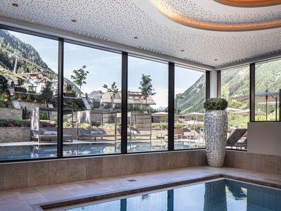 Indoor pool area with large windows overlooking mountains and garden.