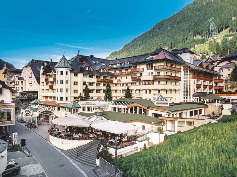 Large hotel with terrace and mountains in the background under clear sky