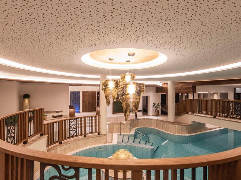 Luxurious whirlpool area with illuminated ceiling and wooden railing in a hotel.