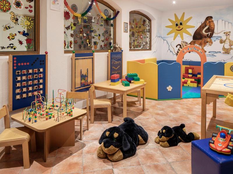 Cozy children's play area with wooden furniture, toys, and colorful decorations in warm lighting.