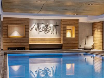 Moderne overdekte zwembad met houten accenten en ontspannende verlichting in een hotel.