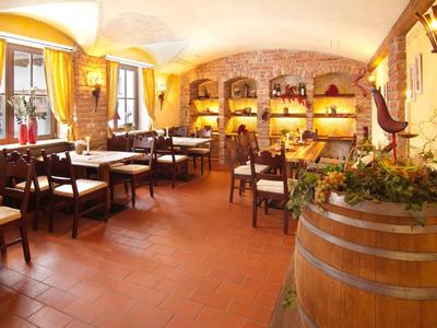 Rustikales Restaurant mit Holzmöbeln, gelben Vorhängen und warmem, gelblich-orangem Licht.