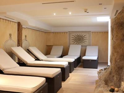 Ruheraum mit Liegestühlen, warmem Licht, beige Wänden und natürlicher Steinwand im Vordergrund.