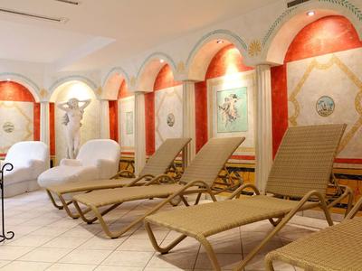 Innenraum mit Liegestühlen, weißen Sofas, armierten Wänden und warmem, indirektem Licht.